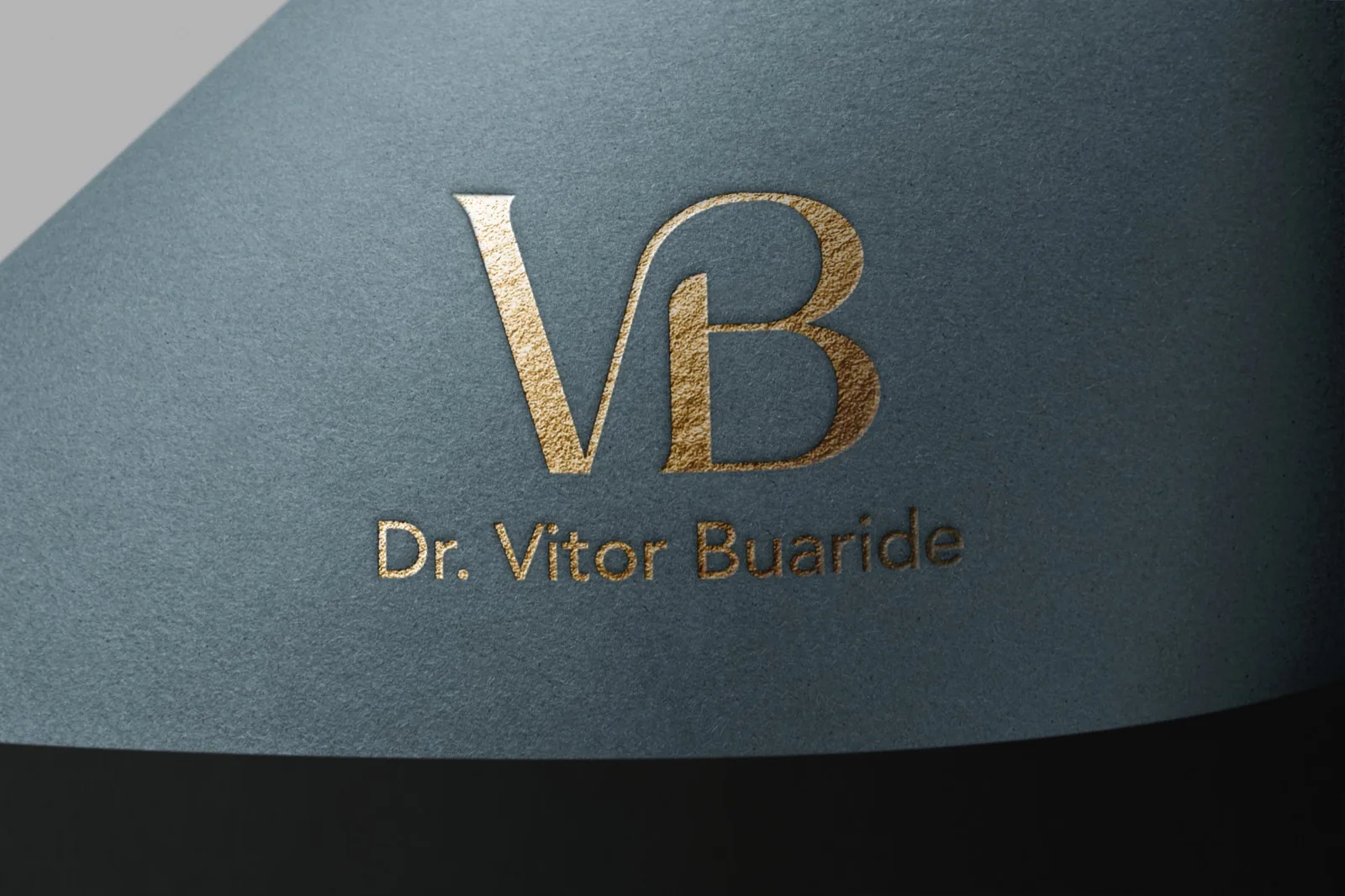 Monograma VB em hot stamping dourado sobre papel texturizado azul-acinzentado